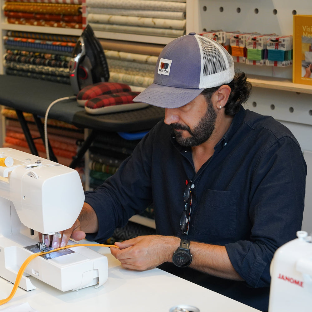 Man working on a sewing machine in a workshop setting