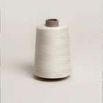 Raw unbleached cotton overlocker spool on cardboard cone with paper wrap., plastic free.