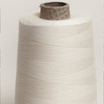 Raw unbleached cotton overlocker spool on cardboard cone with paper wrap., plastic free.